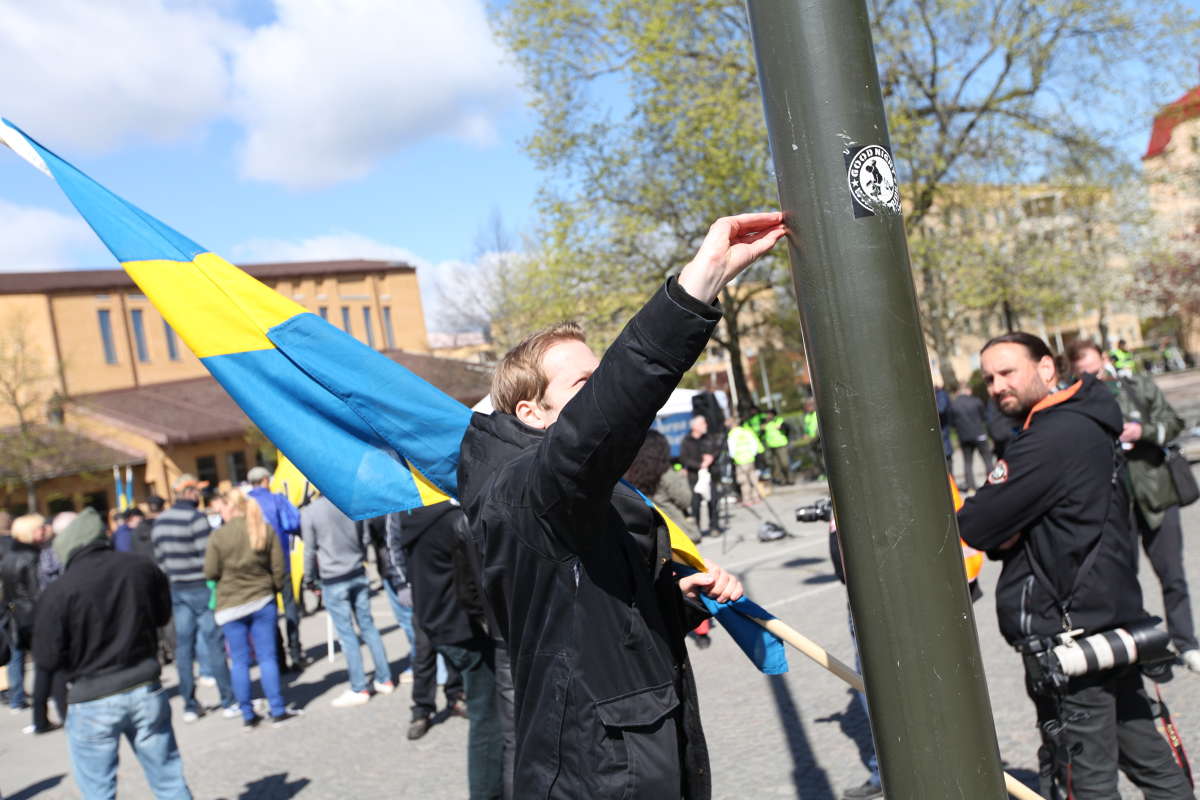 En nazist river bort klisterlappar från en lyktstolpe. En nazist river bort klisterlappar från en lyktstolpe.